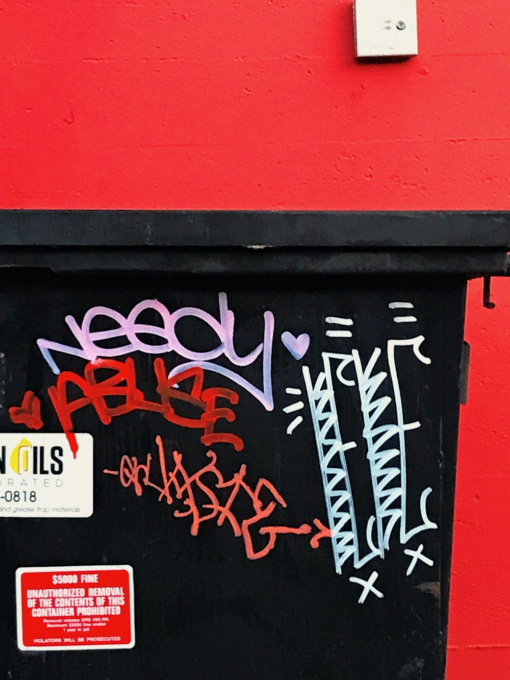 a red wall with a black door and some graffiti on it