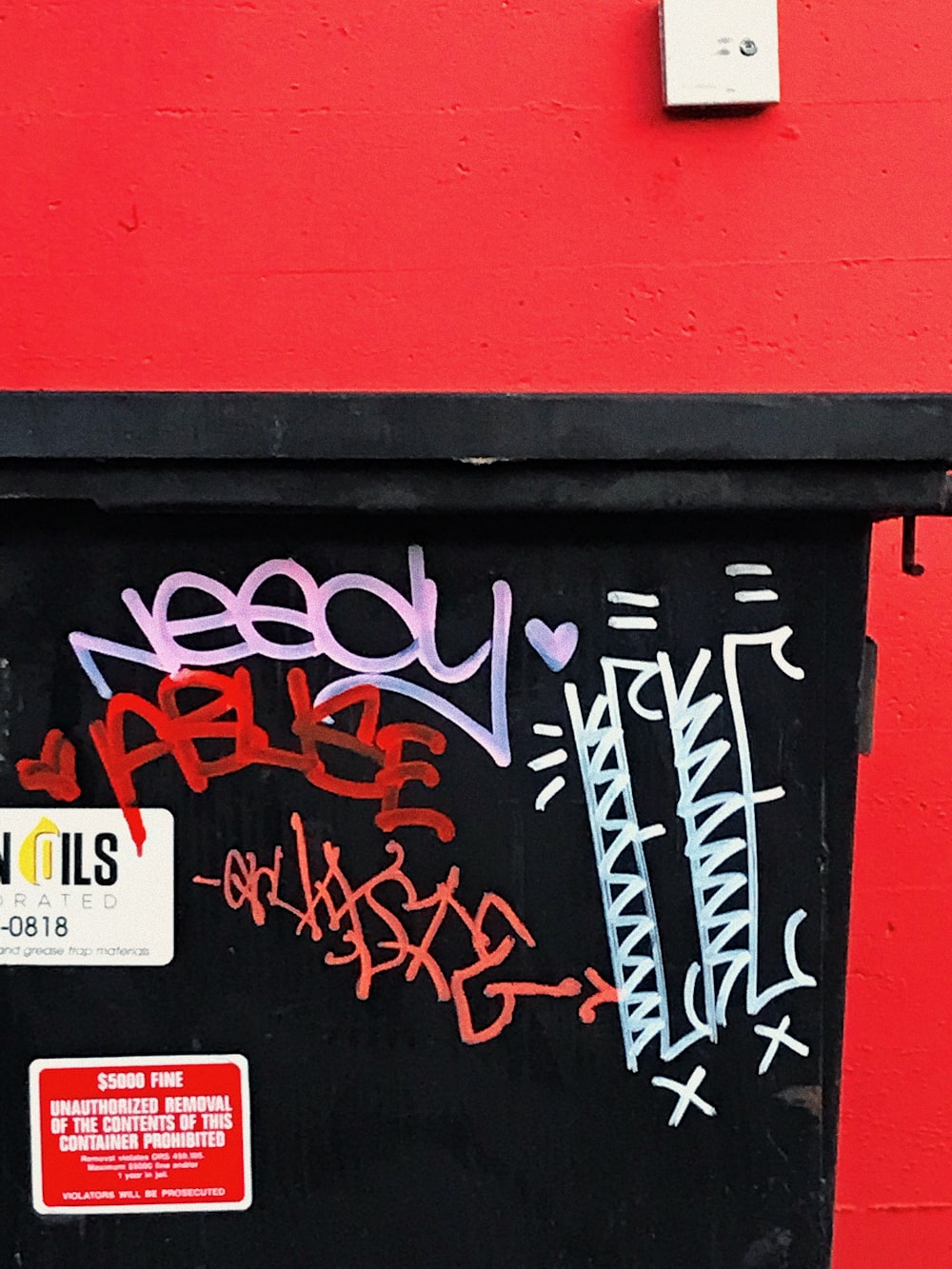 eine rote Wand mit einer schwarzen Tür und einigen Graffiti darauf