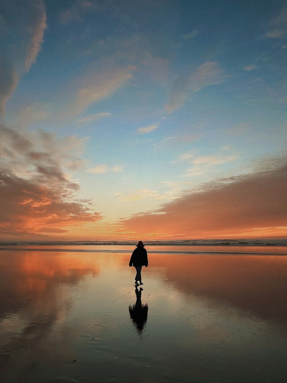 a person walking on a beach at sunset