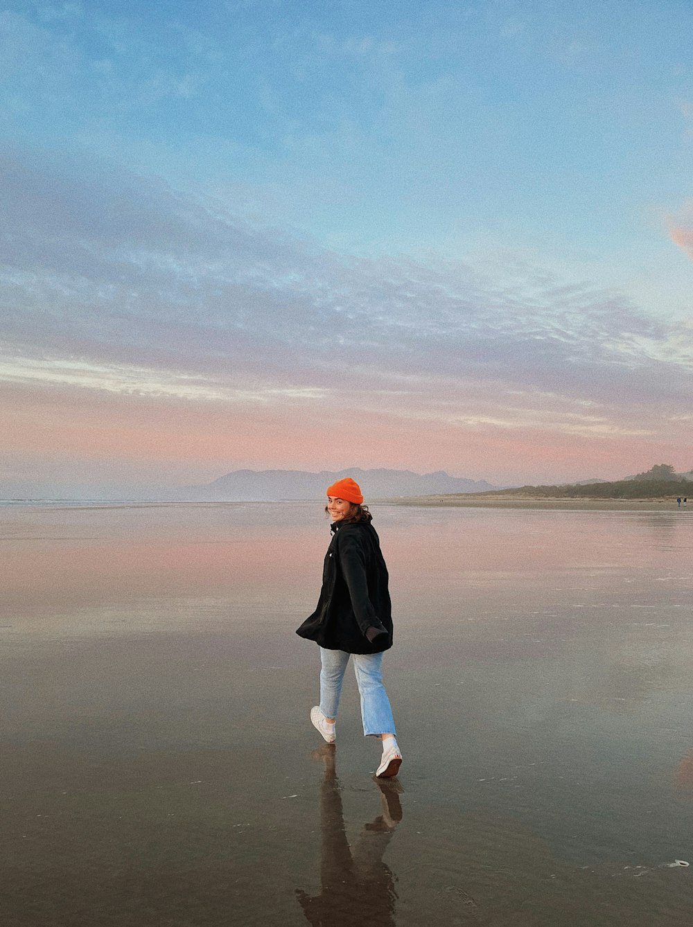 a woman standing on a beach next to the ocean