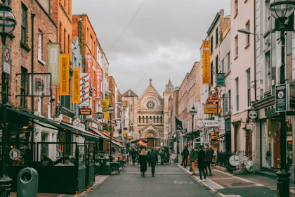 Pedestres numa rua de Dublin ladeada por prédios de tijolo