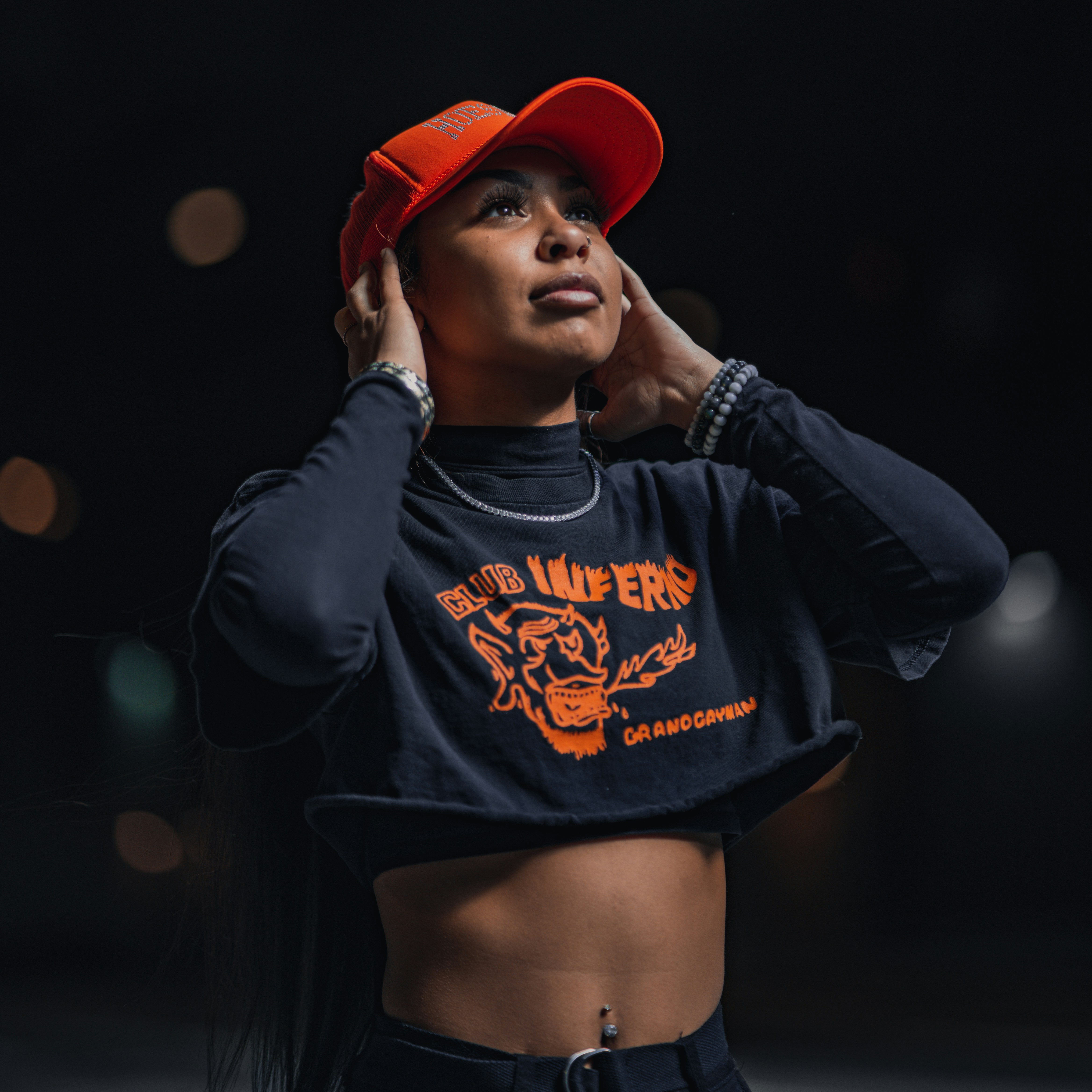 Eine Frau trägt ein schwarzes Crop-Top und einen roten Hut