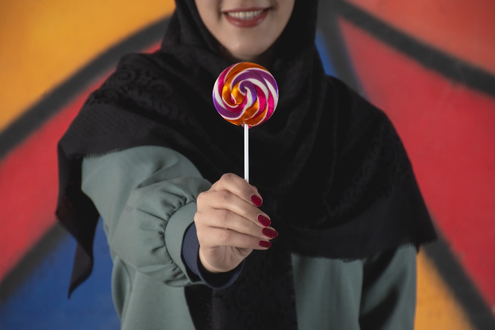 a woman holding a lollipop in her hand