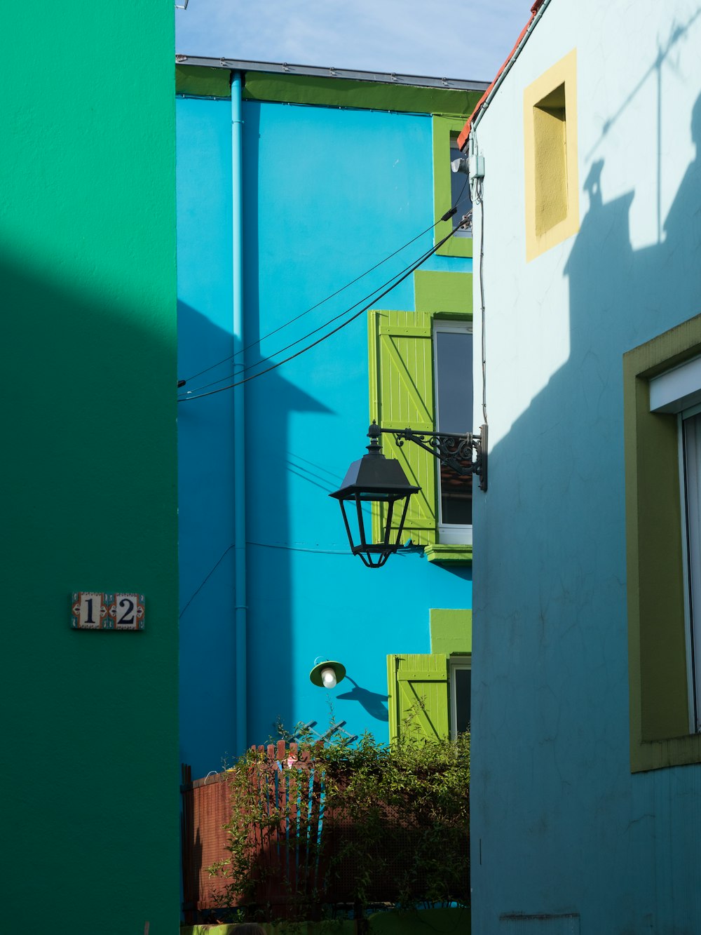 a blue and green building with a lamp on the side of it