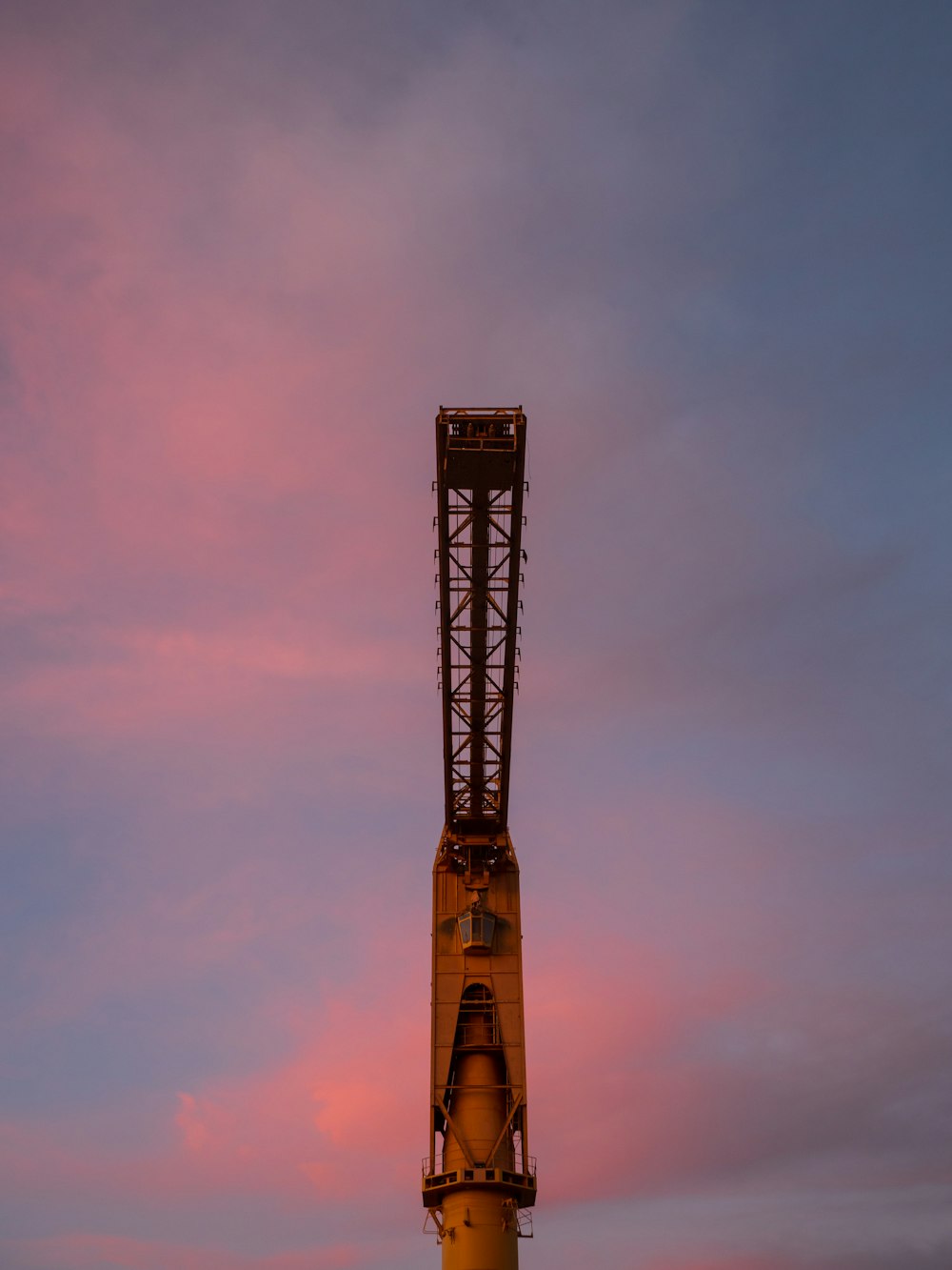 une grande grue posée au sommet d’un poteau métallique