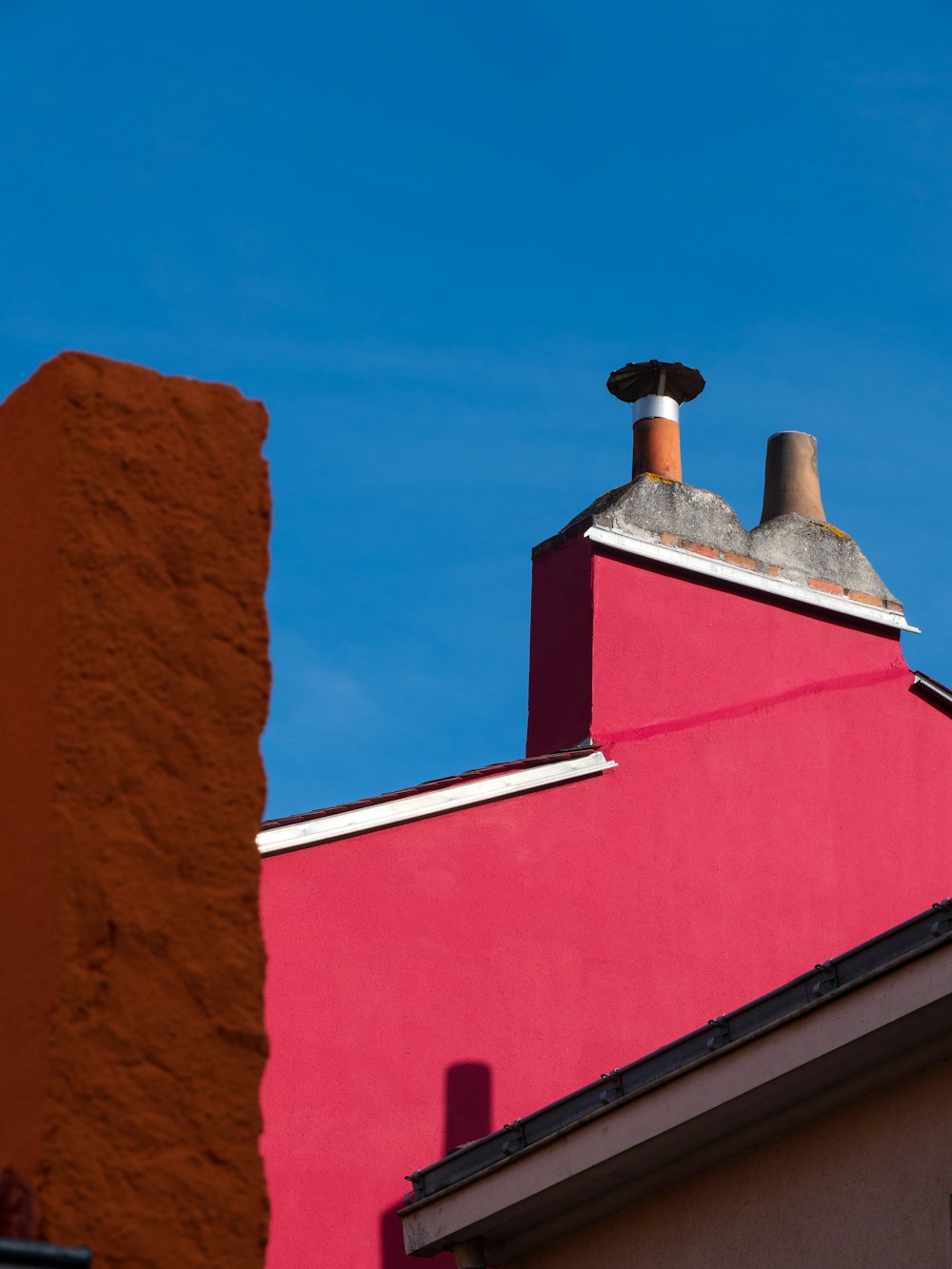 a red building with two chimneys against a blue sky