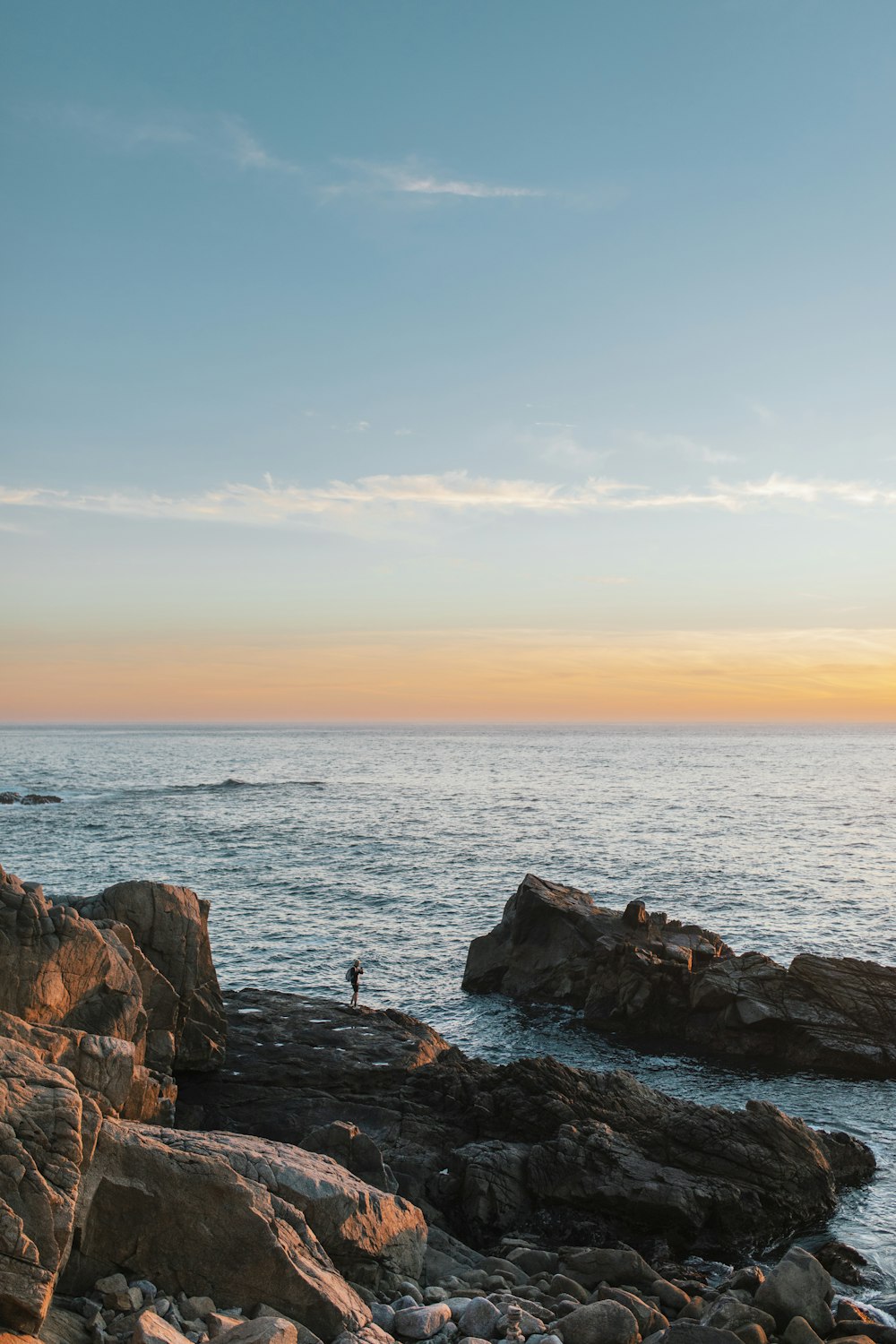 a person standing on a rocky beach next to the ocean