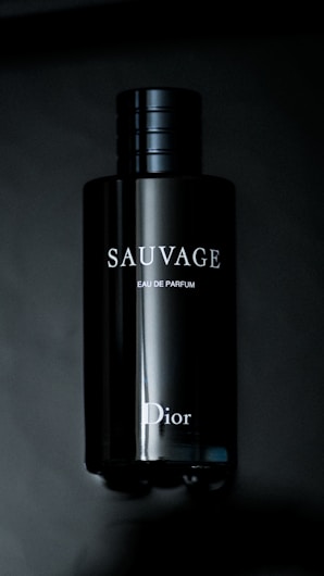 A sleek, dark bottle of fragrance with the brand name 'Sauvage' and 'Dior' visible in white letters. The bottle has a shiny, reflective surface and a simple, elegant design.
