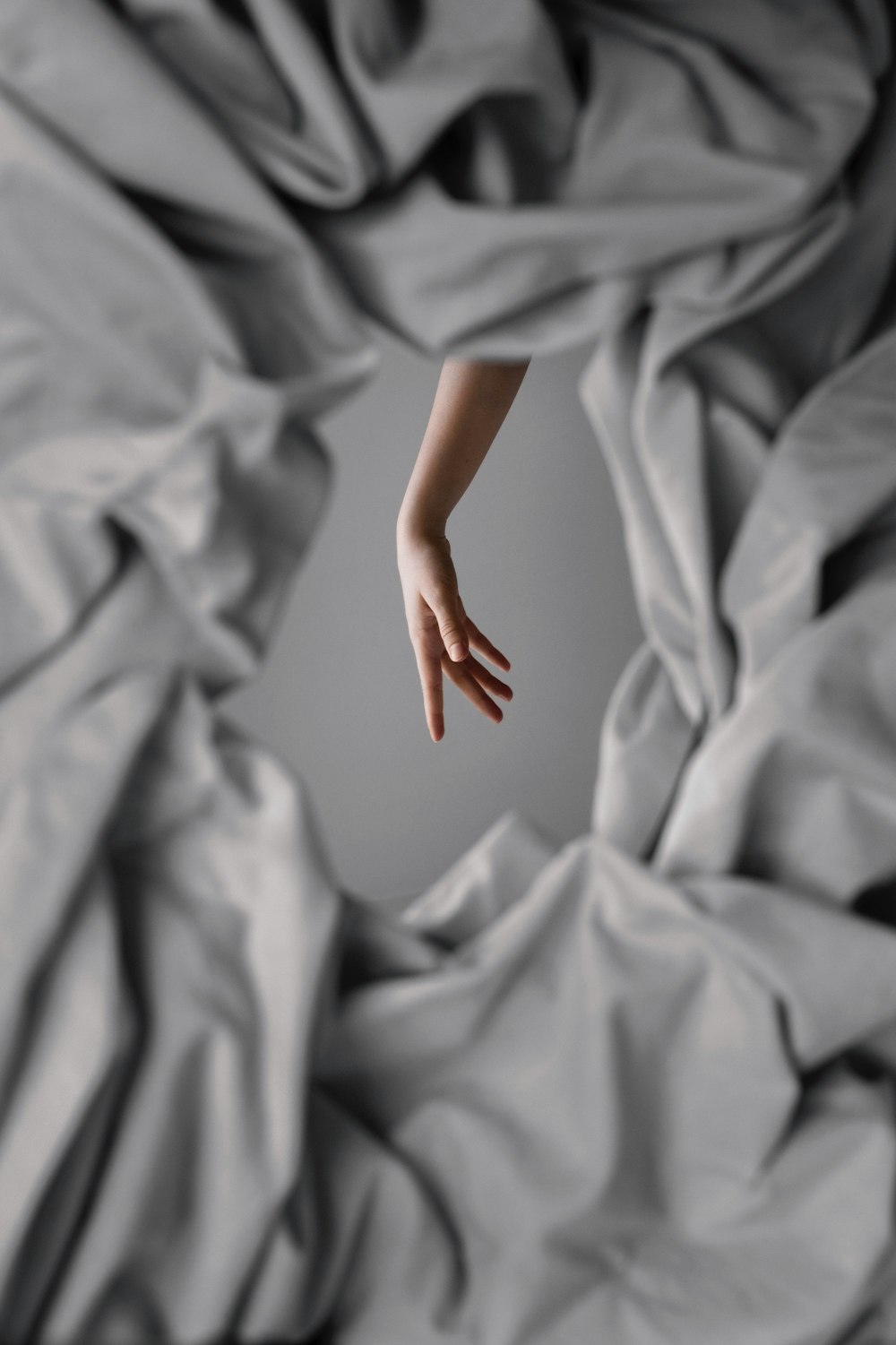 a person's hand reaching out of a blanket