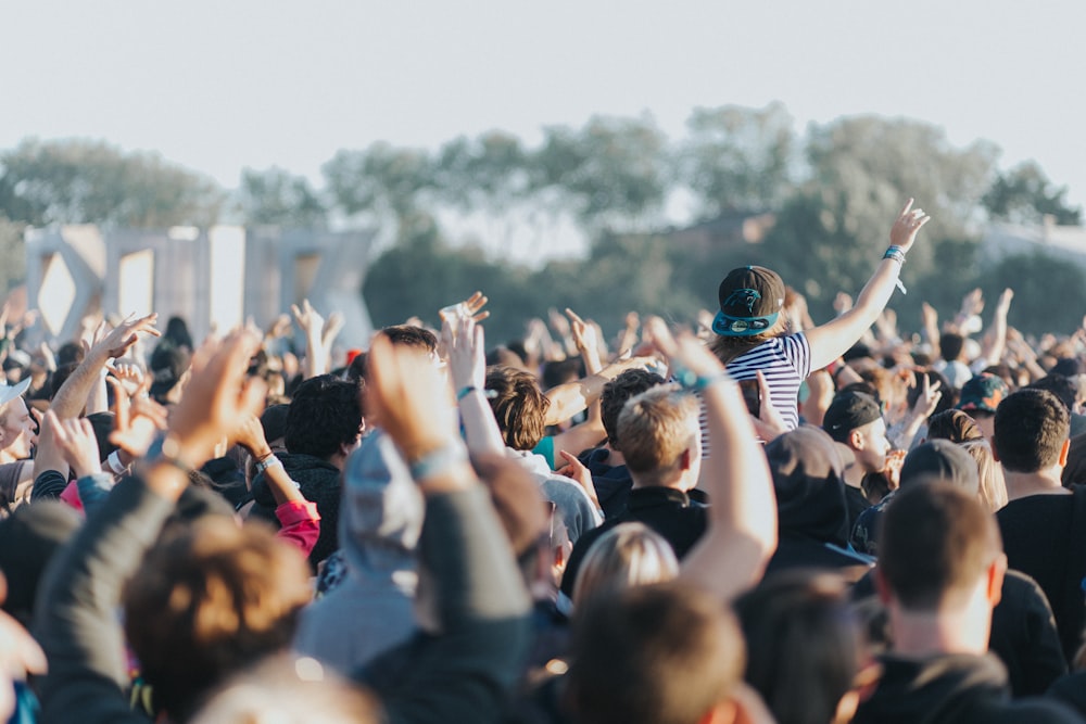 a crowd of people with their hands in the air