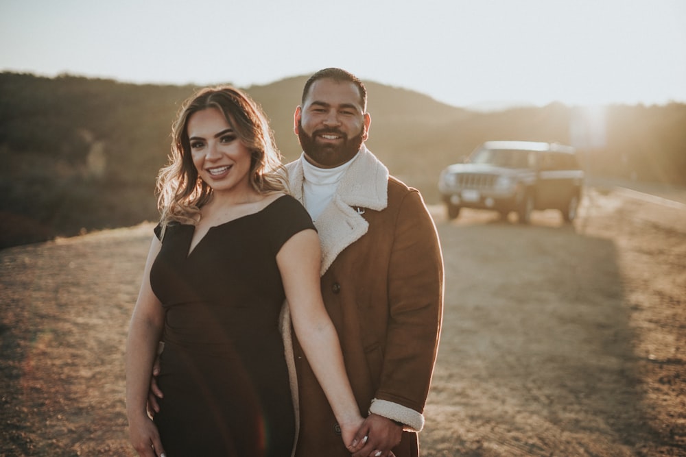 a man and a woman standing next to each other on a dirt road