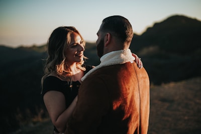 a man standing next to a woman on top of a hill