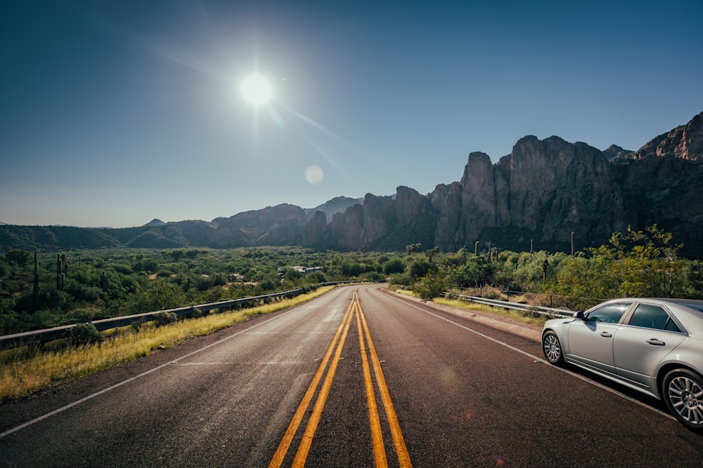 a car driving down a road with mountains in the background