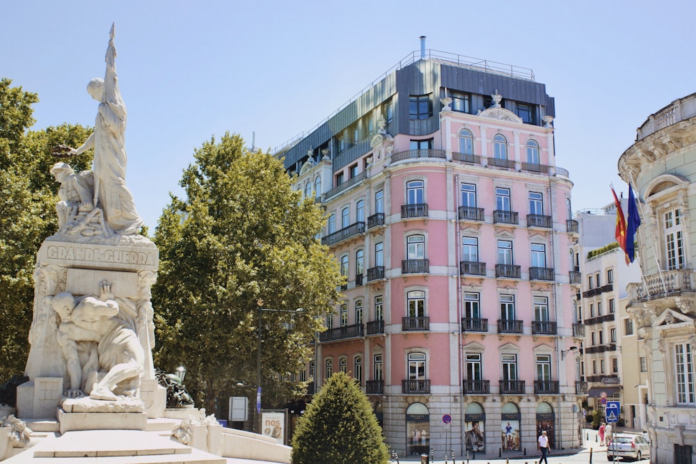 a statue in front of a pink building