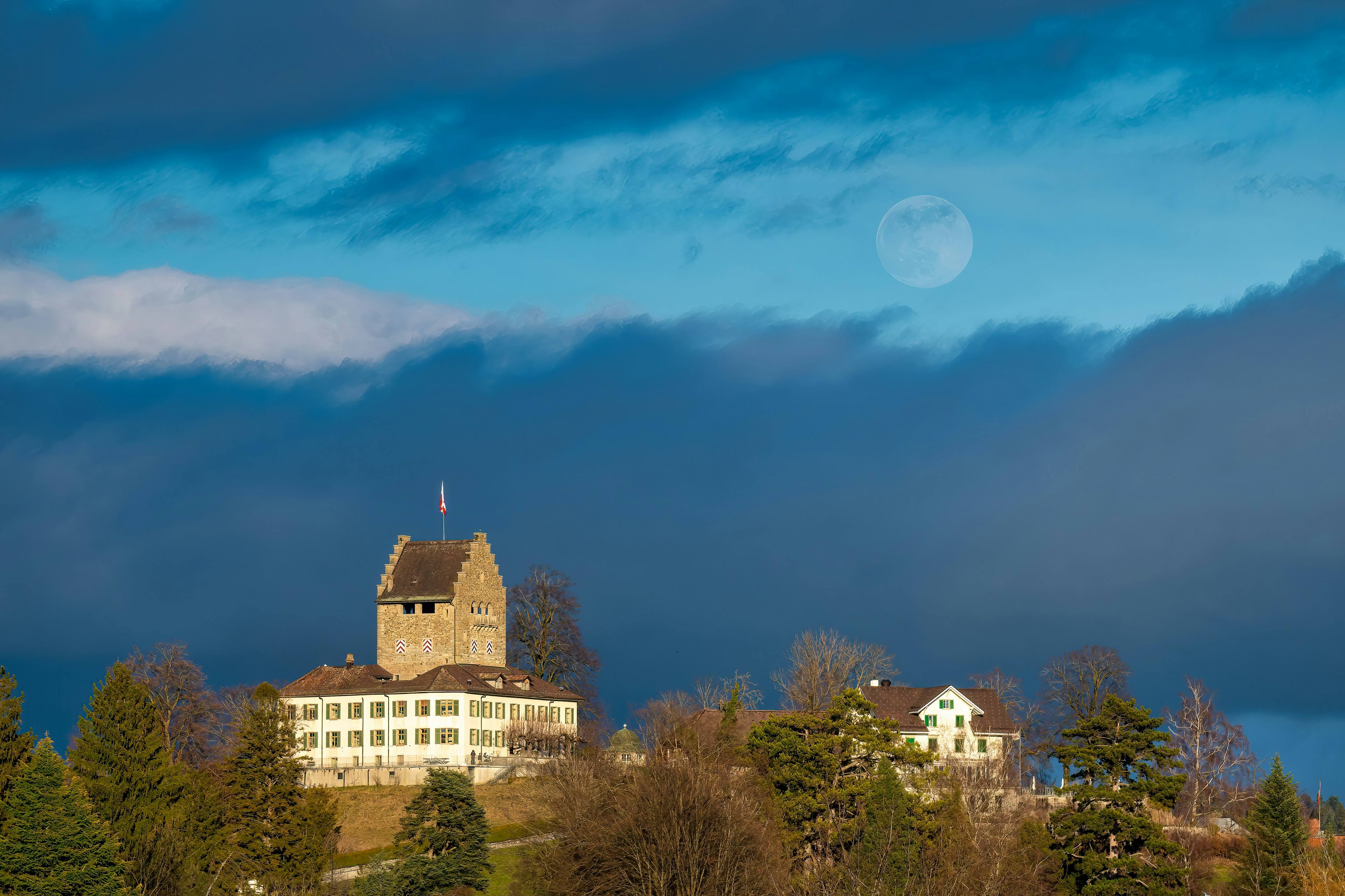 a house on a hill with a full moon in the background