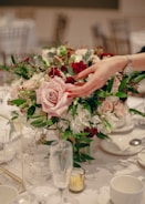 Delicate floral centerpiece with roses and wildflowers in shades of pink and magenta on a white linen cloth.