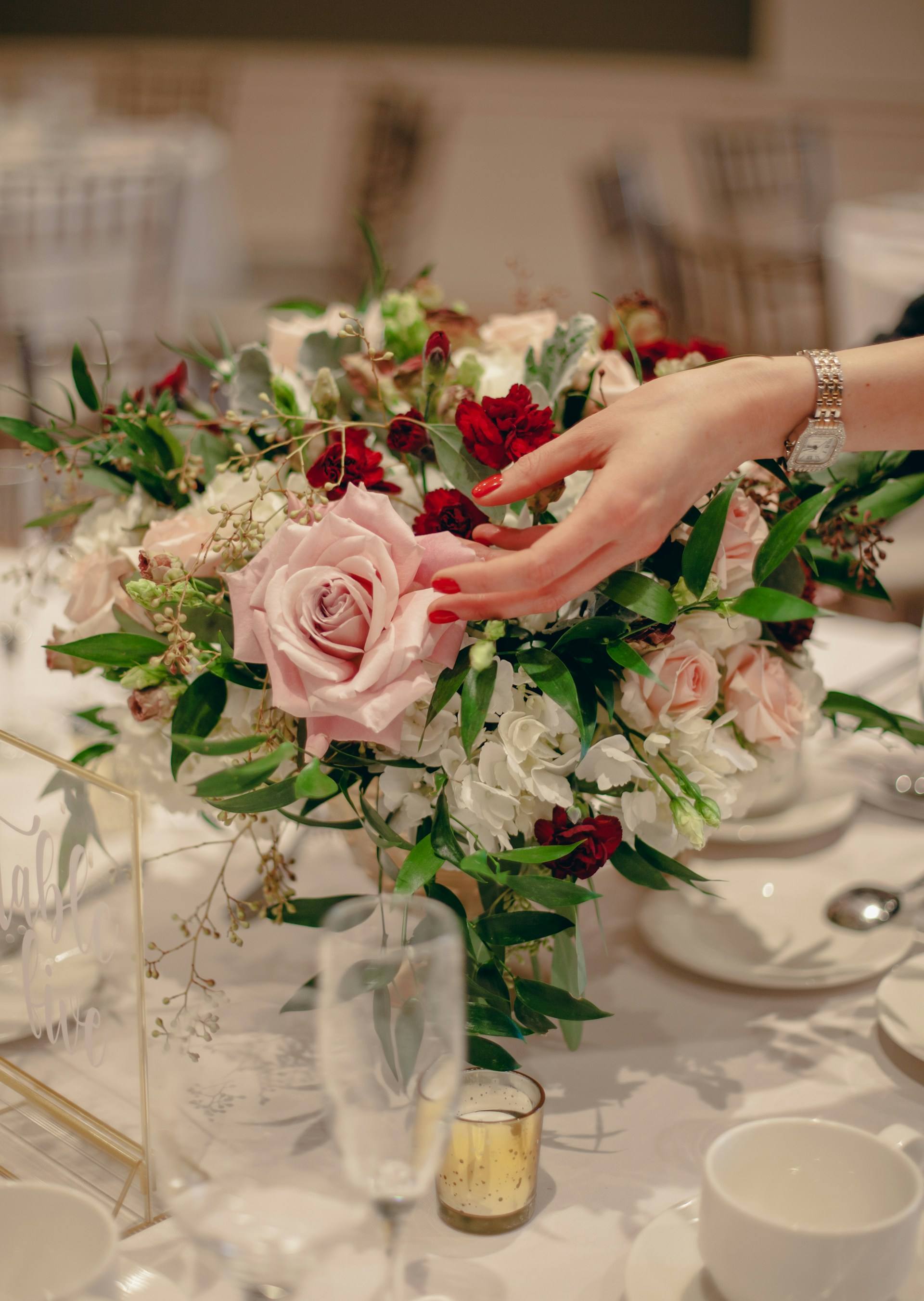 An elegant floral centerpiece bursting with fresh blooms in shades of pink and white, set on a beautifully decorated event table.