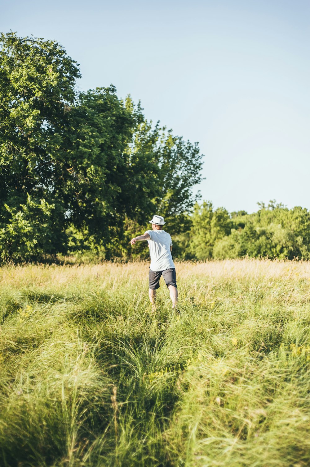 a man standing in a field flying a kite