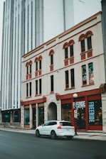 a white car parked in front of a tall building