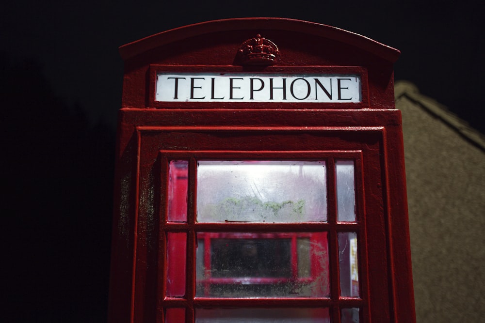 a red telephone booth sitting in the dark