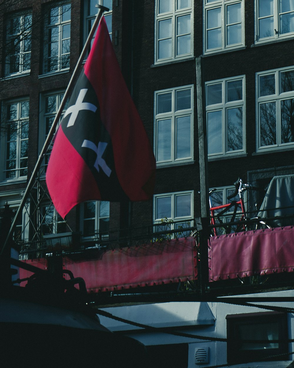 a flag and a bike on a bridge in front of a building