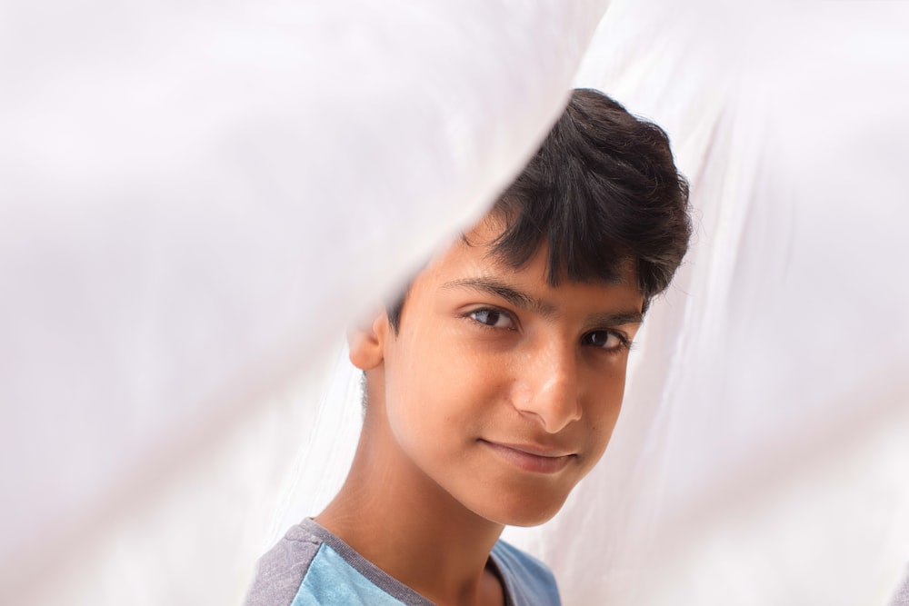 a young boy looking through a hole in a sheet