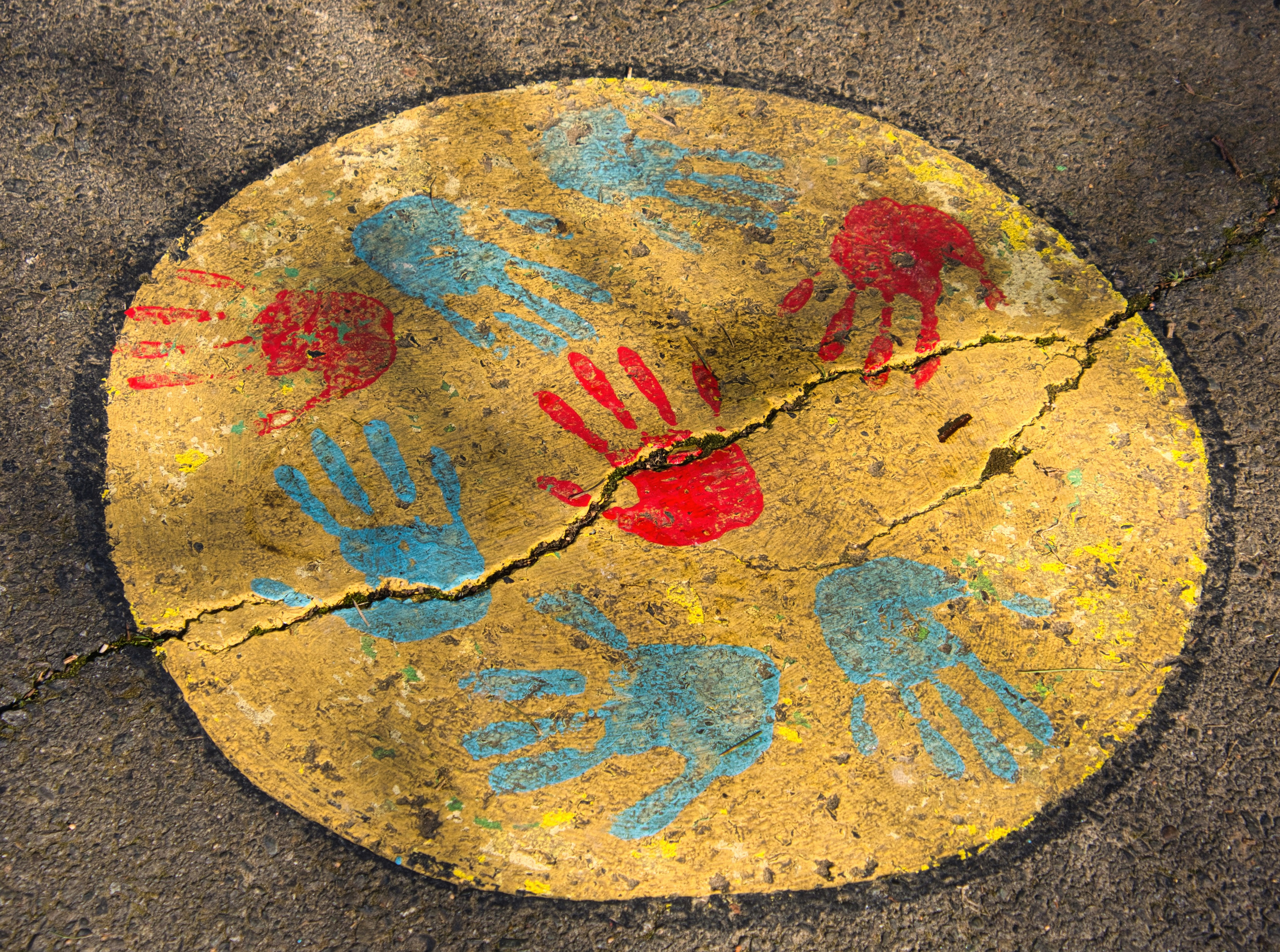 a yellow and blue painted circle with hand prints on it