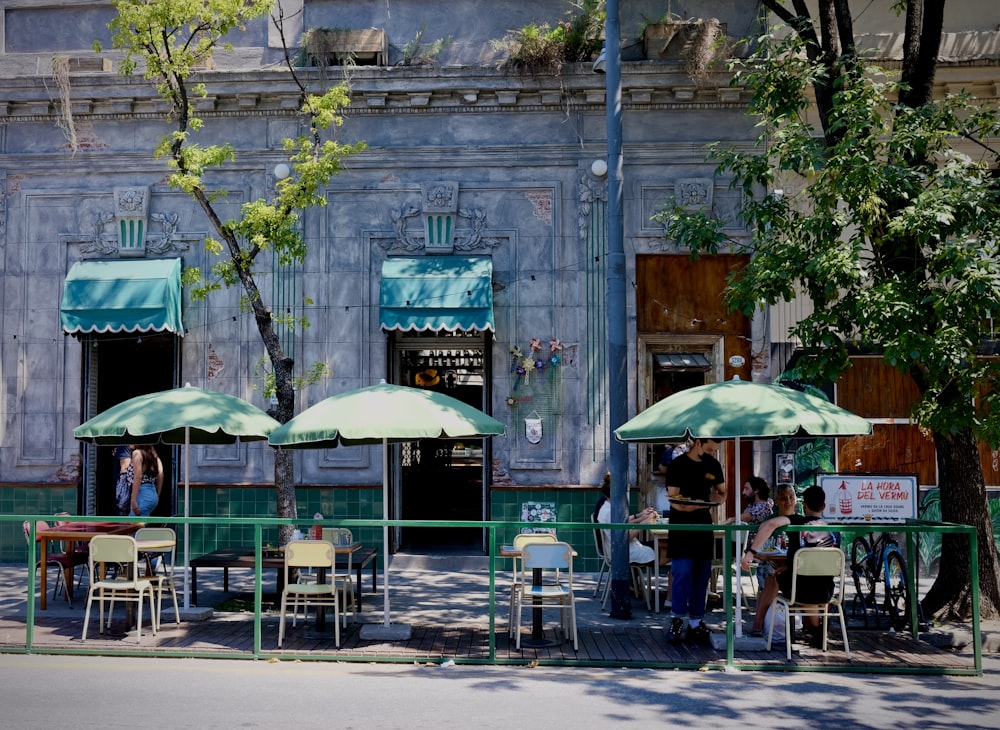 a group of people sitting at tables under umbrellas