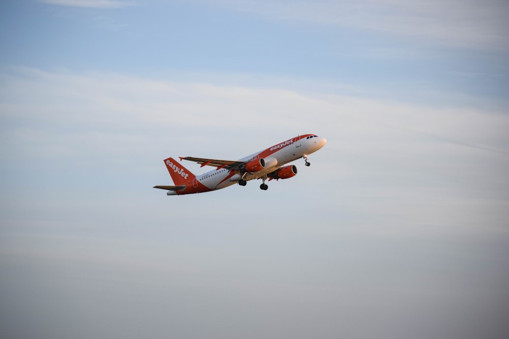 a red and white airplane flying in the sky