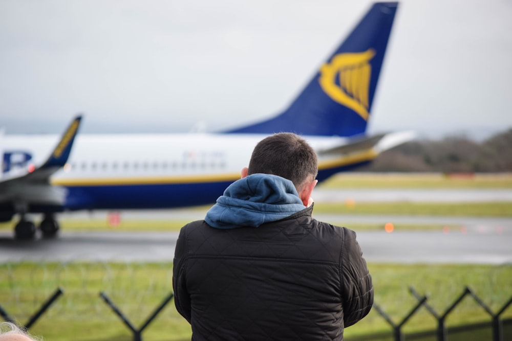 a man looking at a plane on the runway