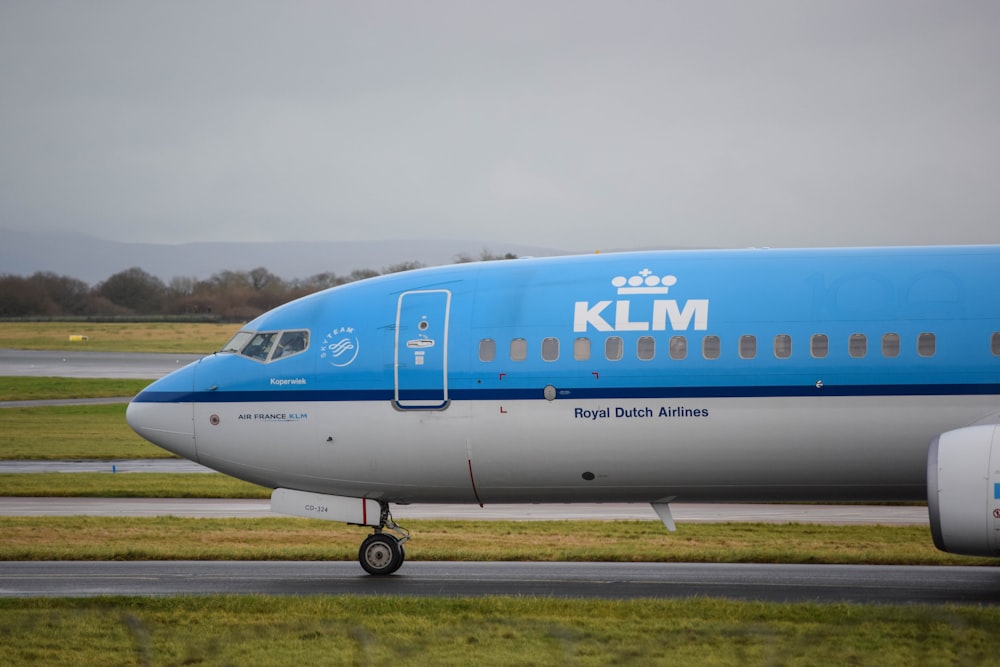 a large blue and white jetliner sitting on top of an airport runway