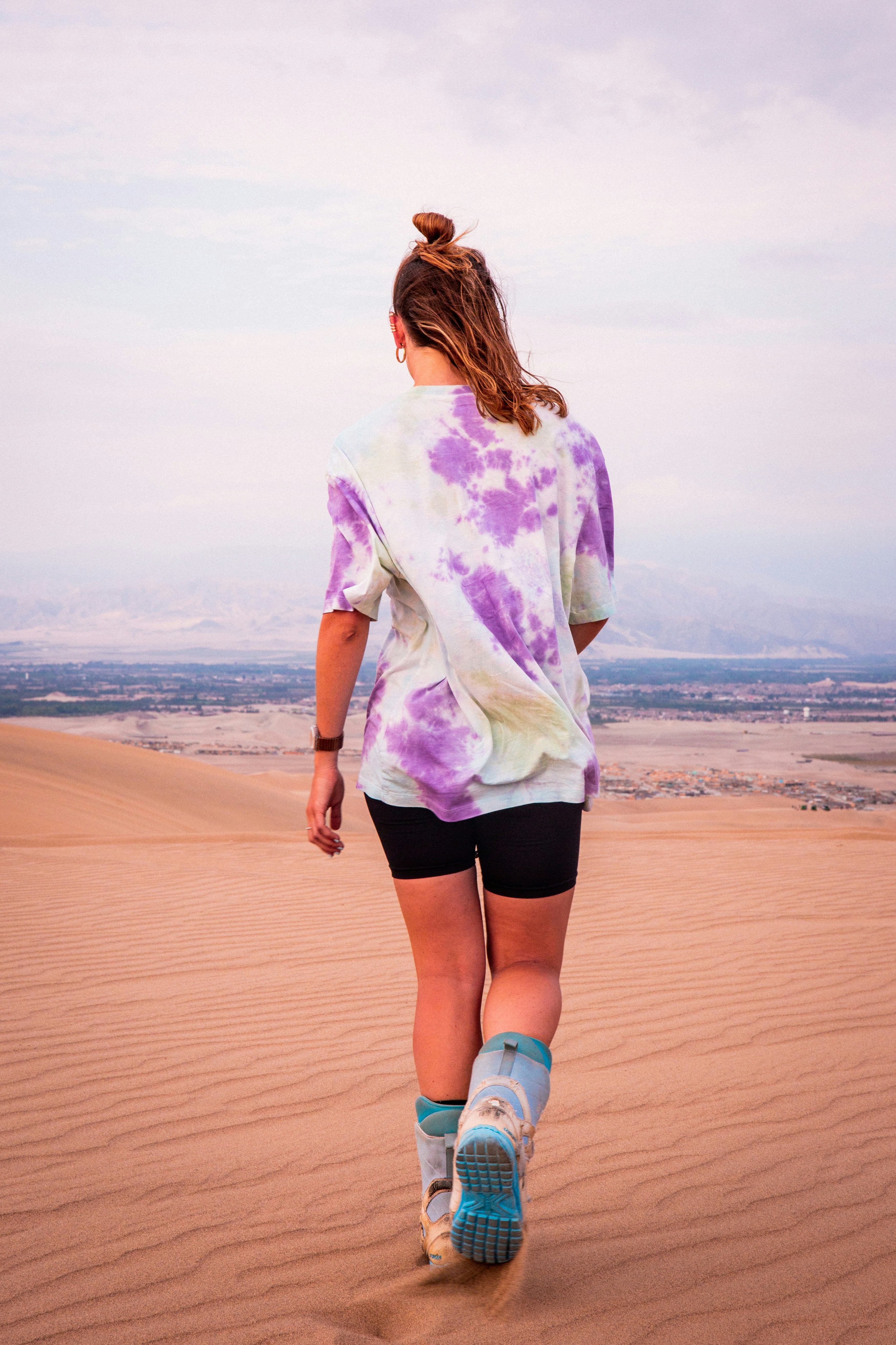 a woman walking across a sandy field