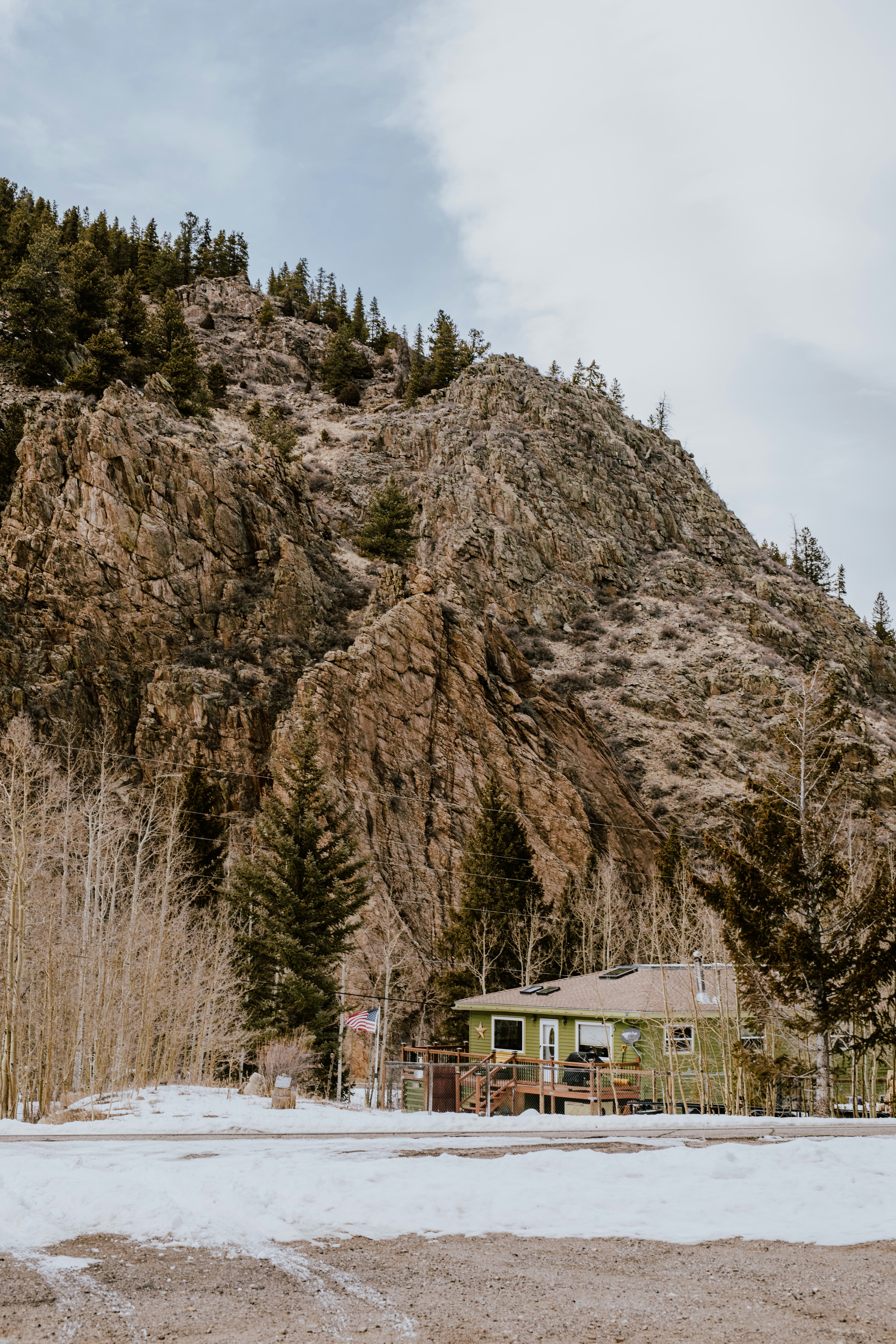 a house in front of a mountain with snow on the ground