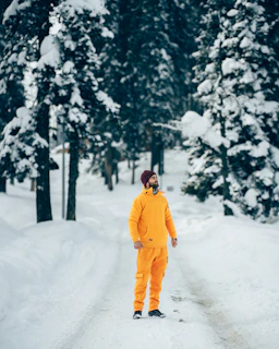 a man in an orange jumpsuit standing on a snowy road