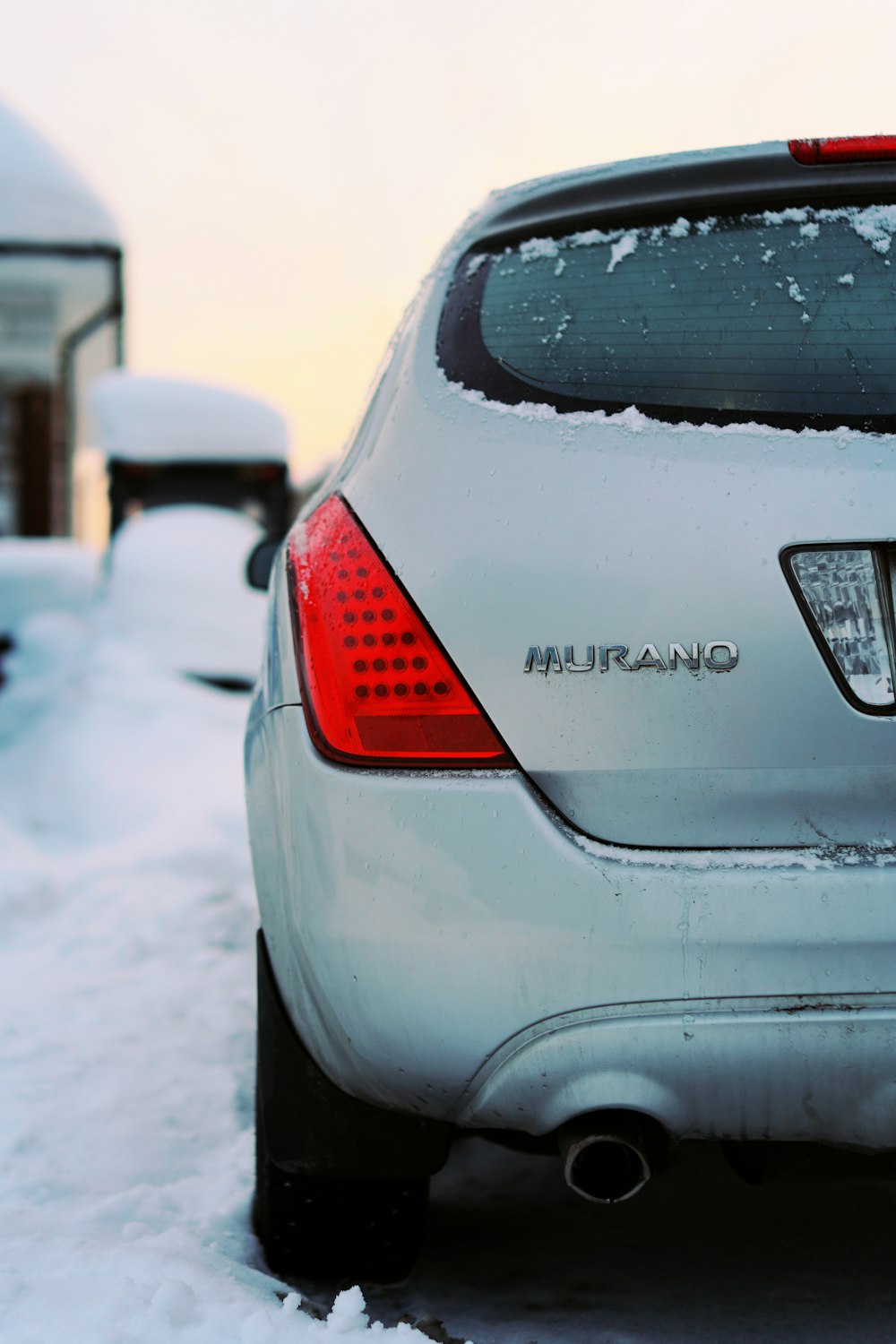 a silver car parked in the snow next to a house