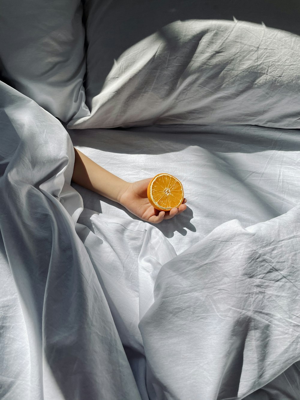 a person laying in bed with an orange slice in their hand