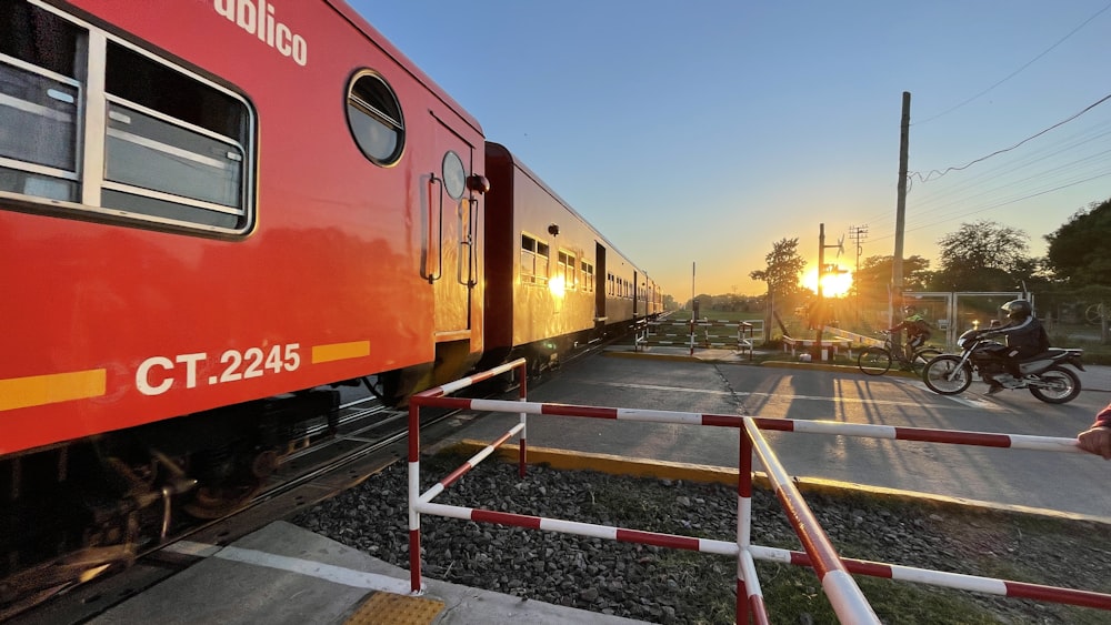 a red train traveling down train tracks next to a person on a bike