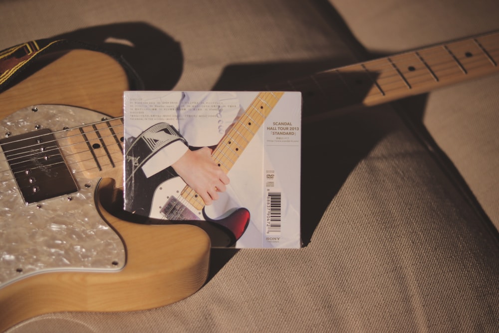 a guitar sitting on a couch next to a magazine