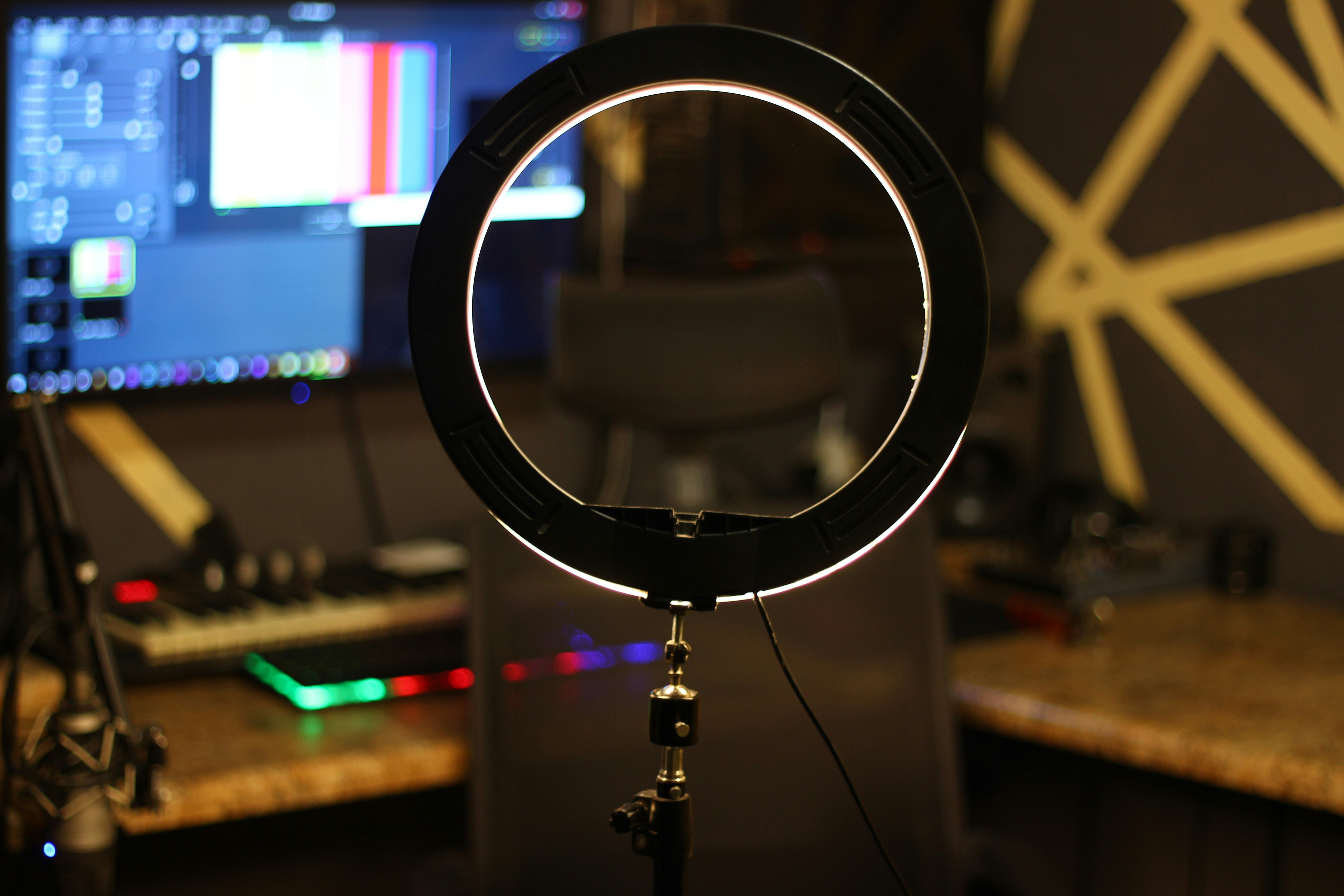Well-lit home studio setup with ring light, camera, and monitor displaying video editing software, bright professional environment