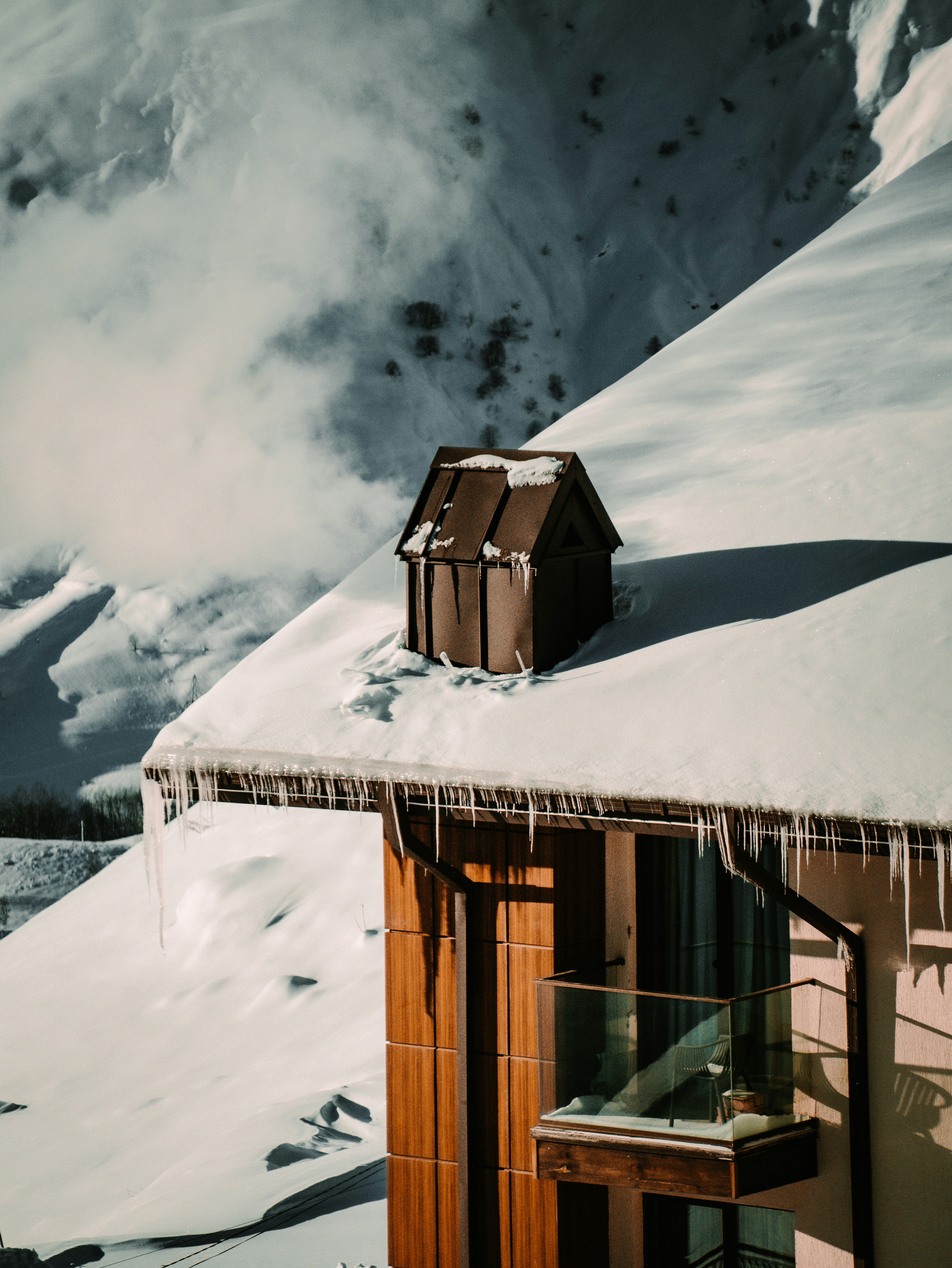 a house covered in snow next to a mountain