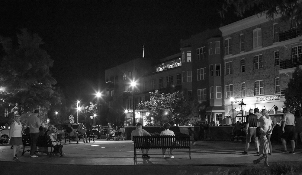 a black and white photo of people sitting on a bench