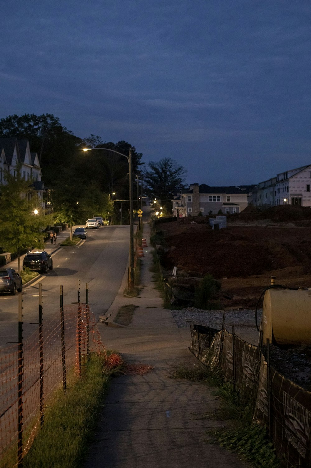 a street at night with cars parked on the side of the road