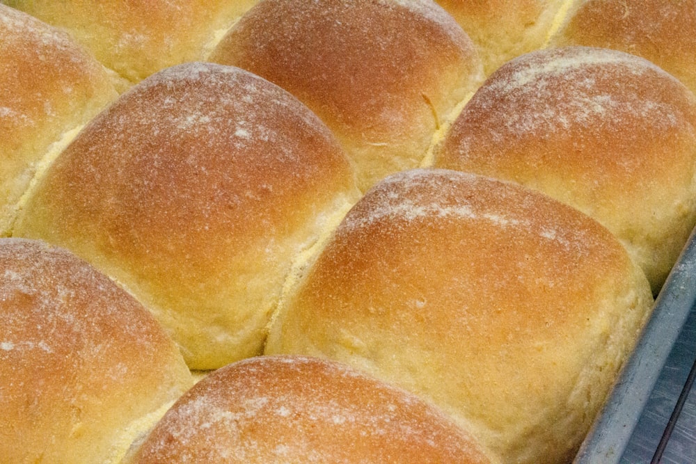 a baking pan filled with bread rolls covered in powdered sugar