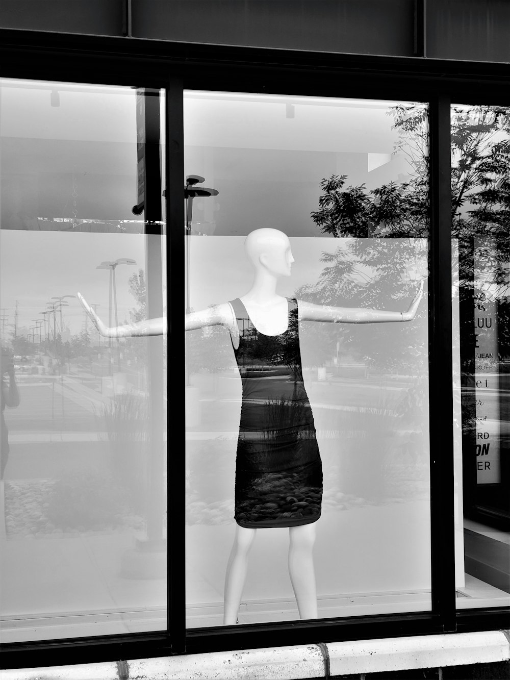 a black and white photo of a mannequin in a window