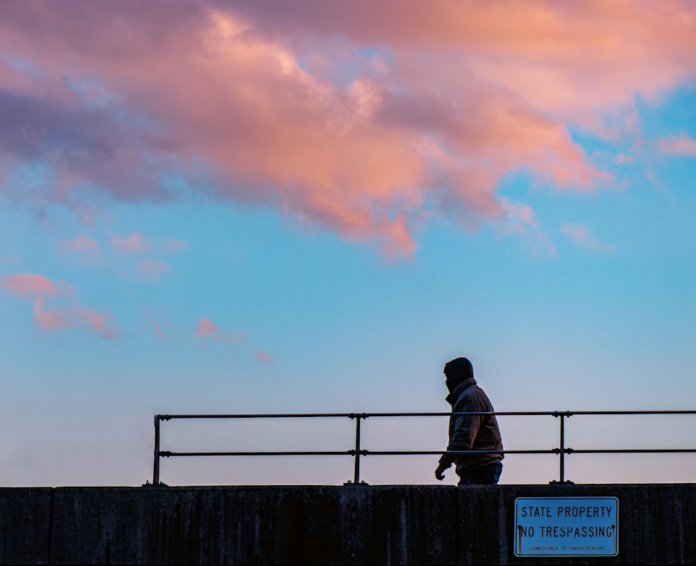 a person standing on a bridge watching the sky
