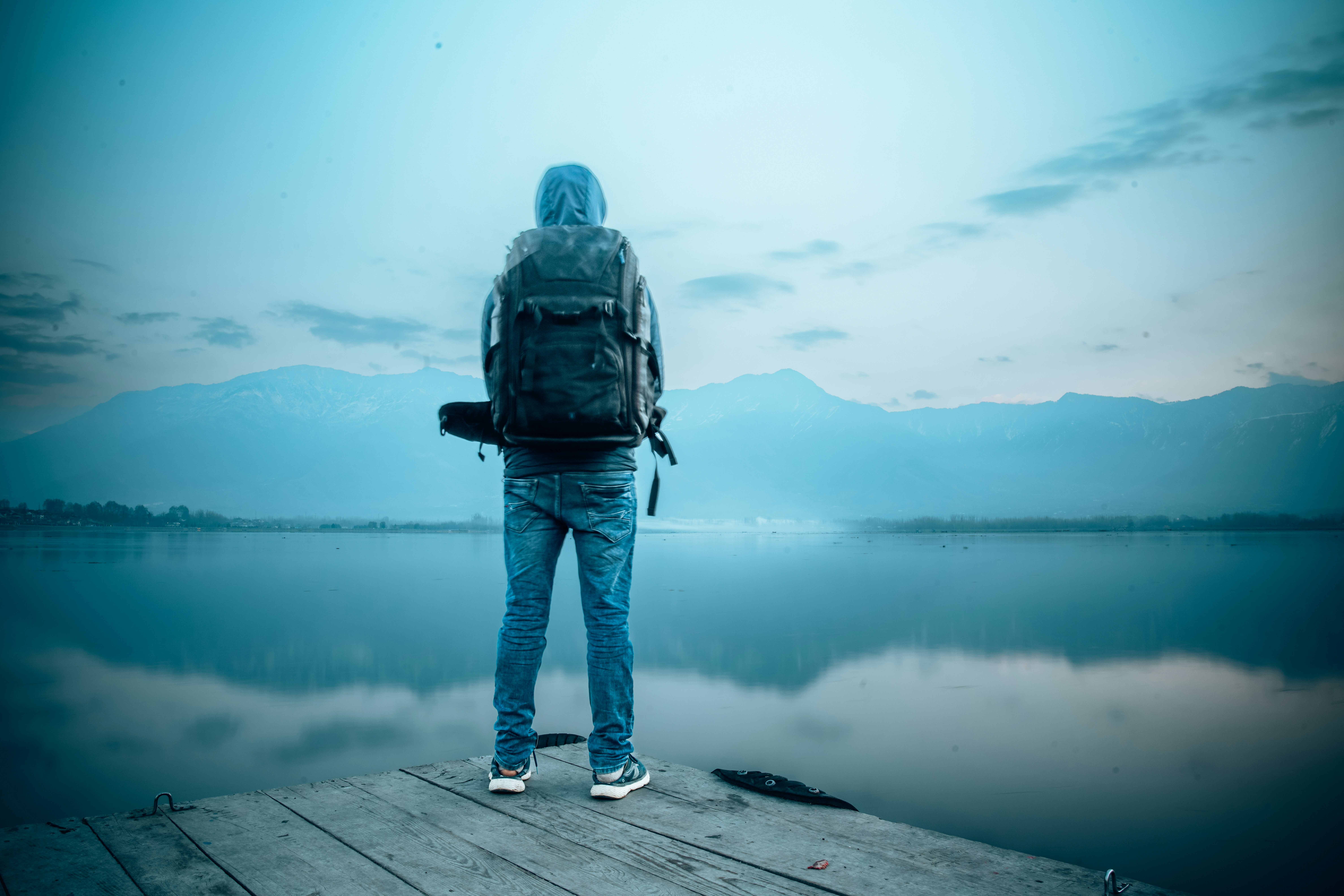 una persona in piedi su un molo con uno zaino