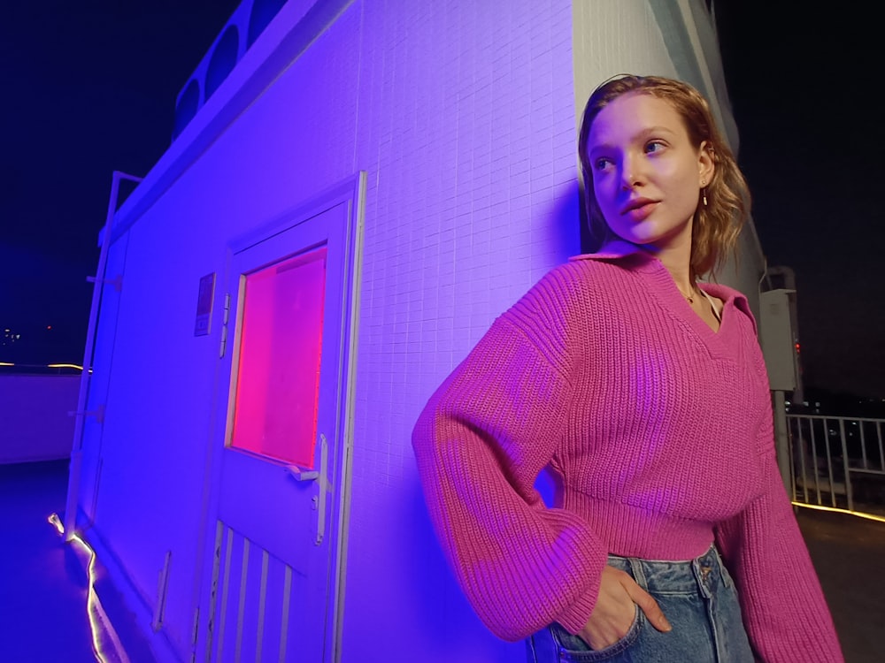 a woman standing next to a building with a purple light