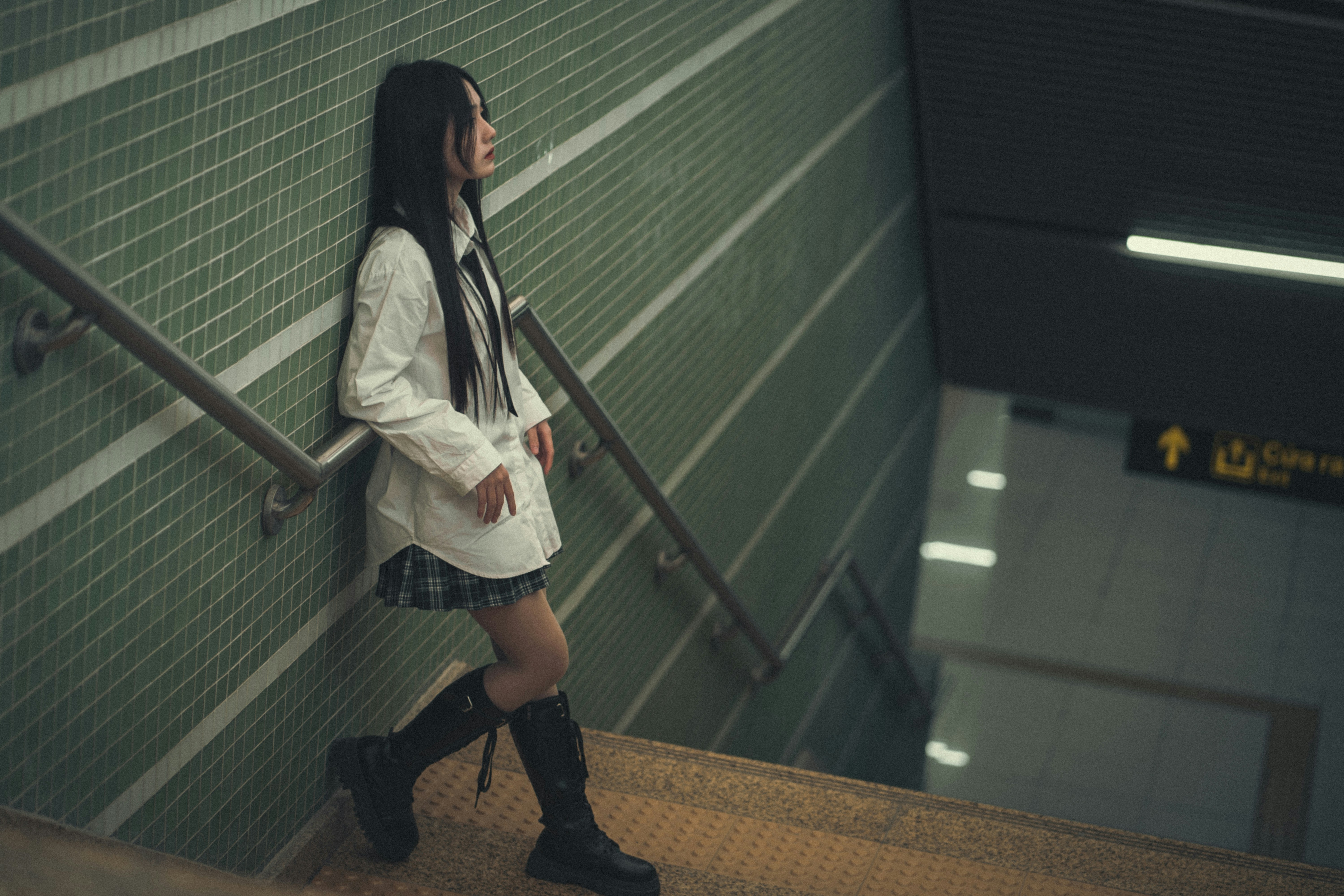 a woman in a short skirt and boots is standing on a set of stairs