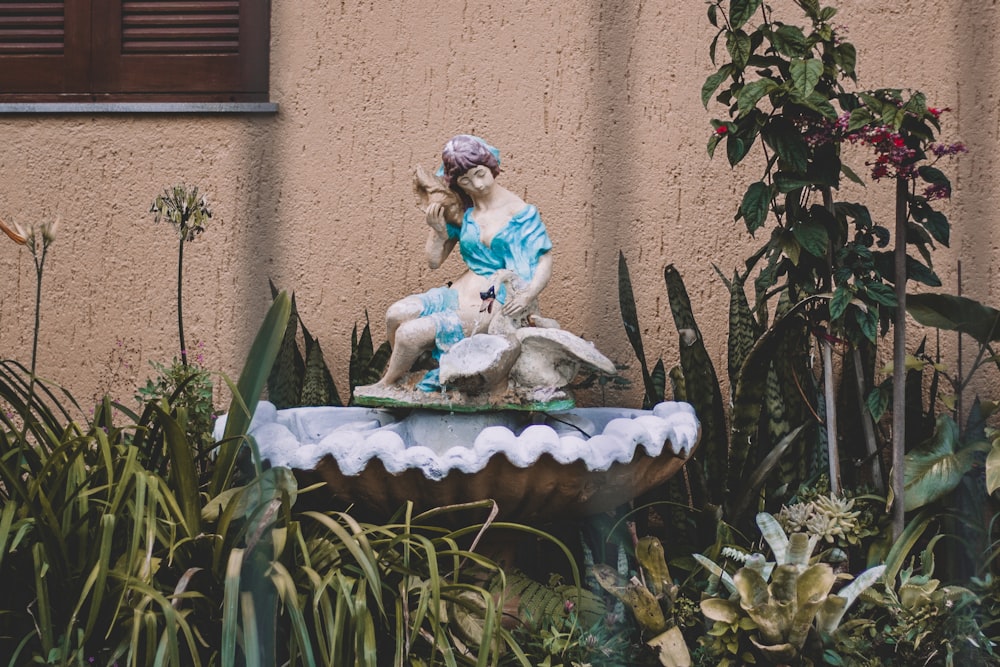 a statue of a woman sitting on top of a fountain