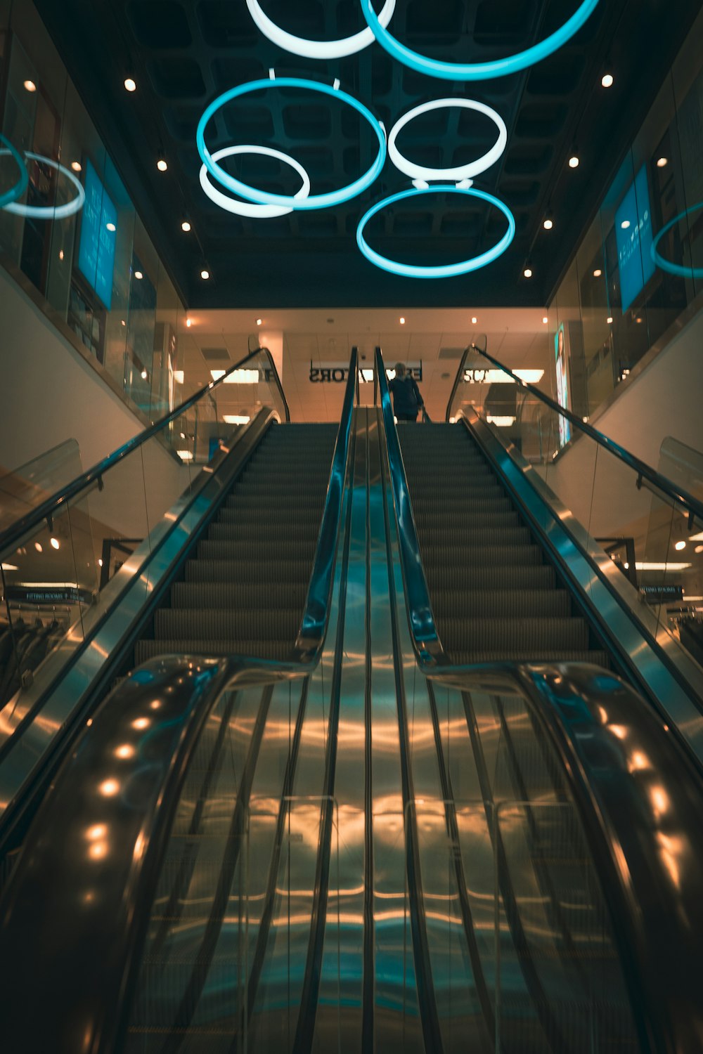 an escalator in a building with blue lights